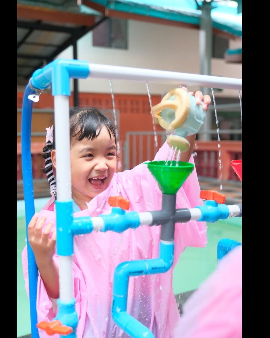 กิจกรรม water play: น้องเรนโค้ทชมพูยิ้มดีใจเล่นกรวยน้ำและท่อน้ำ PVC ที่โรงเรียนมณีอนุสรณ์ศึกษา